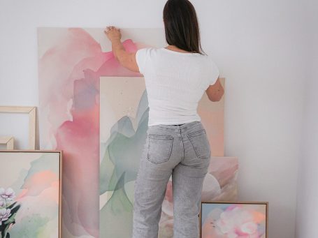 Kunstwerke von Anca Juliana Anca Juliana hält ein abstraktes Kunstwerk vor sich, umgeben von weiteren Bildern.