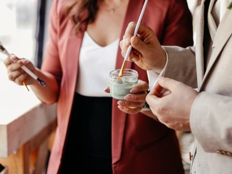 Detaillierte Zeichnung – Auftragsarbeit – Auftragskunst Eine Person mit blonder Haarfarbe geht mit zwei braunen Hunden – Dackeln –am Strand spazieren.