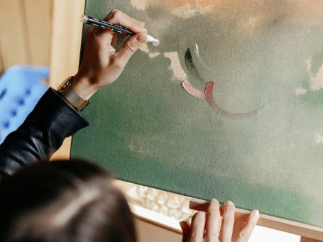 Wedding-Painting – Hochzeitsmalerei – Künstlerisches Gästebuch Hände halten einen Pinsel und malen auf einer Leinwand während einer Hochzeit.